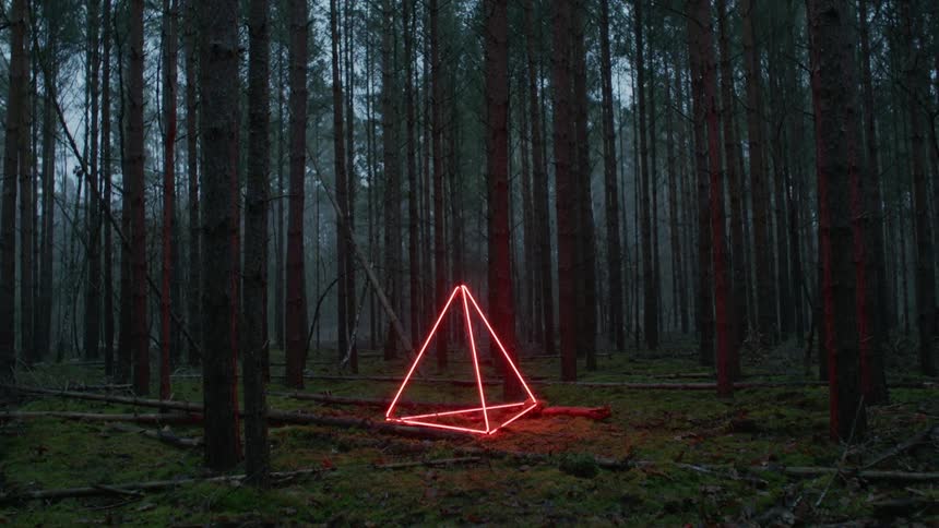 A triangle glowing with neon lit sits in a forest