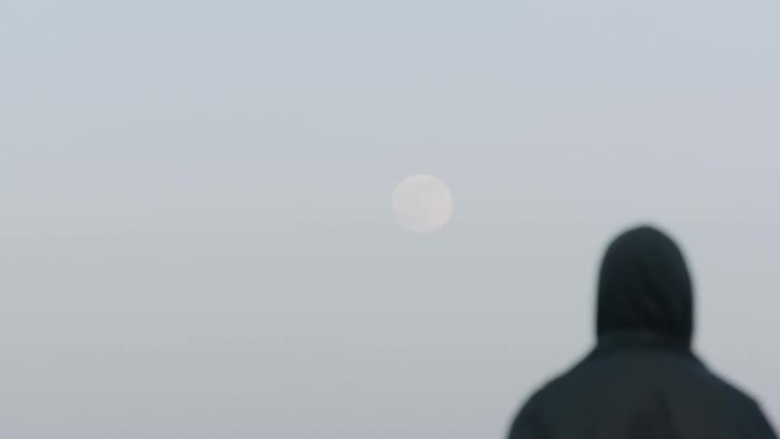 Man with a black hoodie watches the moon