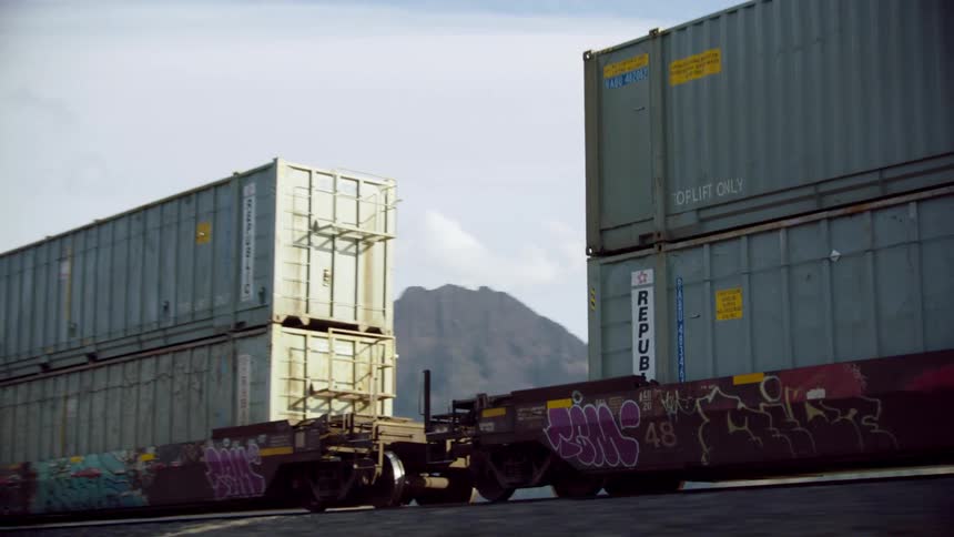 A freight train hauls towering containers of goods across America as heavy industry keeps the economy open