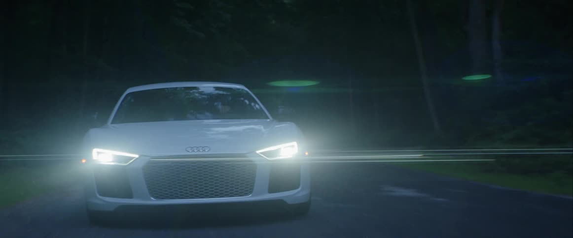 A vehicle is driving down a street in a dark area