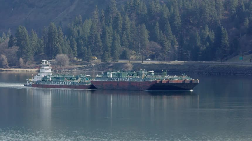 Transport ship pushes a barge on the Columbia River with I-84 visible in the background as commerce moves goods to and from port