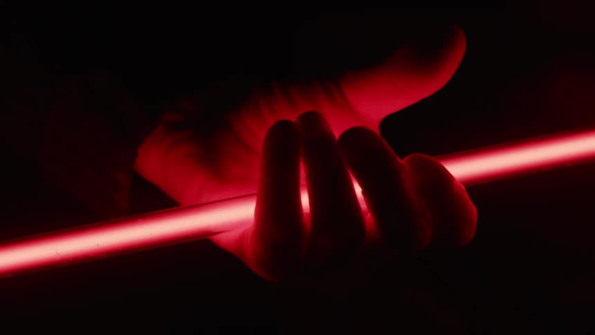 A white man closes his hand over a long rod of light