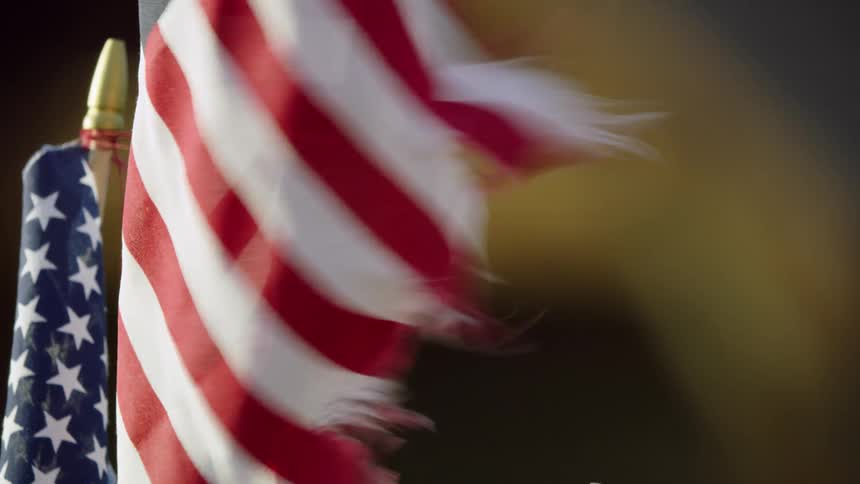 A tattered American flag blows in the wind in front of an old abandoned farm house deep in rural America