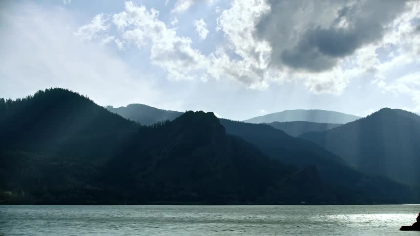 Sun rays illuminate the Columbia River Gorge in late afternoon light as the vehicle travels down the highway before being obscured by a passing truck