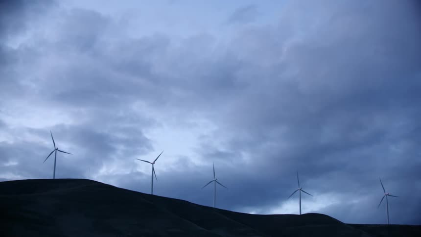 Five wind turbines create power under a purple and moody sky in rural America as the camera passes by rapidly