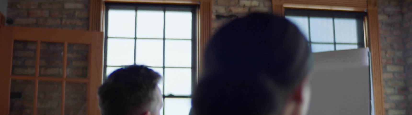A man carries a coffee mug into a meeting room with other employees