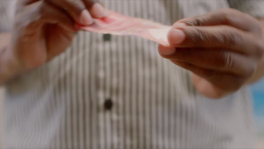 Black man with a striped shirt holds money banknote and starts walking
