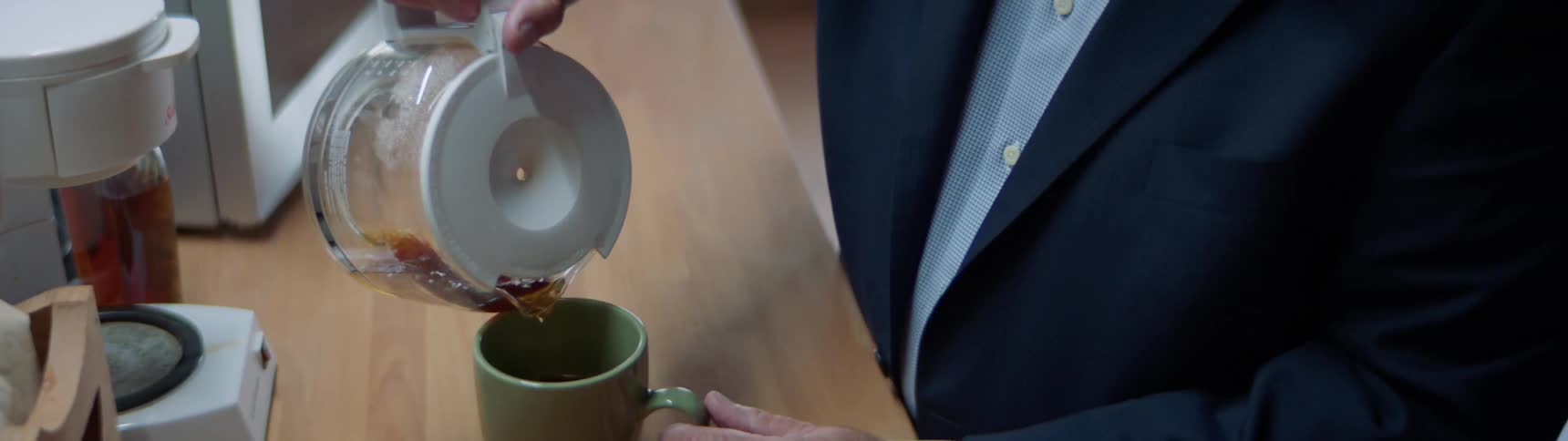 An elderly man pours himself a cup of coffee