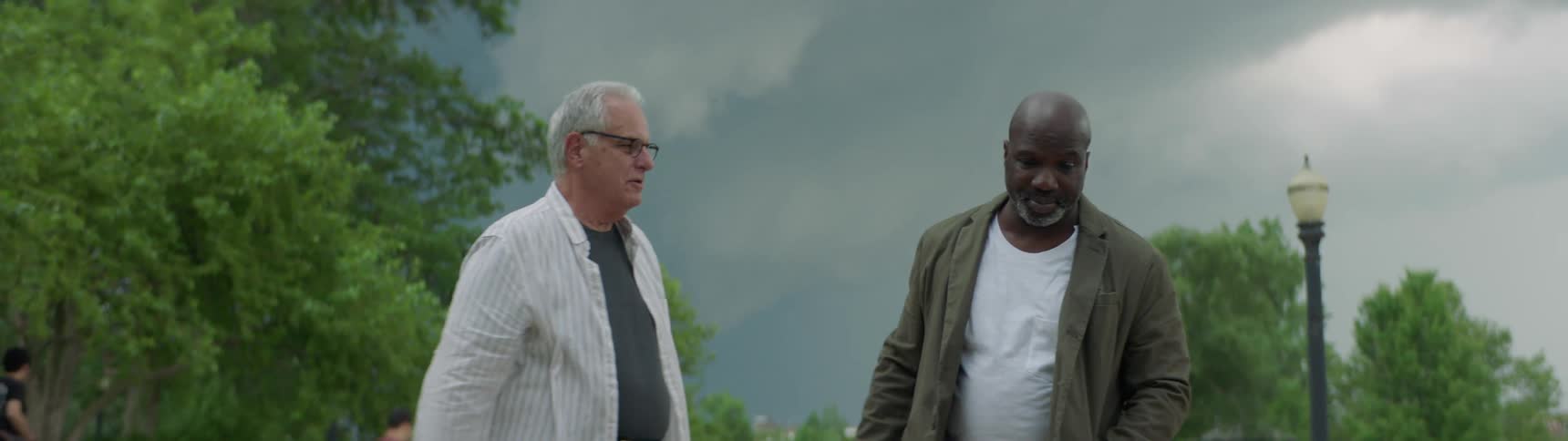 A black man and white man shake hands and walk together