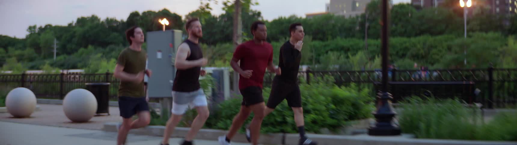 Four men run on a trail in the park