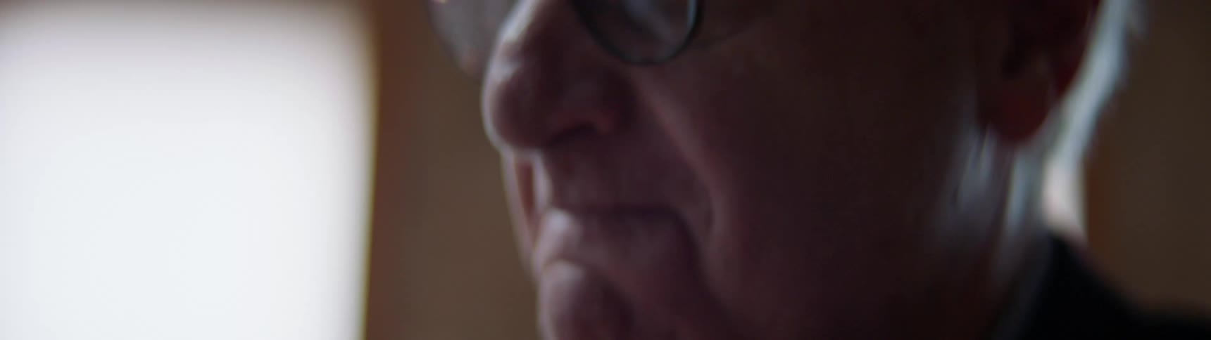 Older man drinking coffee then shaking his head in disapproval