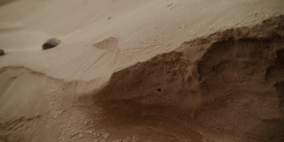 Sand blows off the top of a sand dune