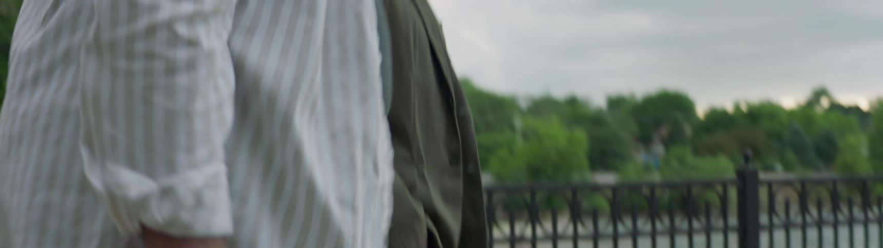 Two men walk together beside a small town pond