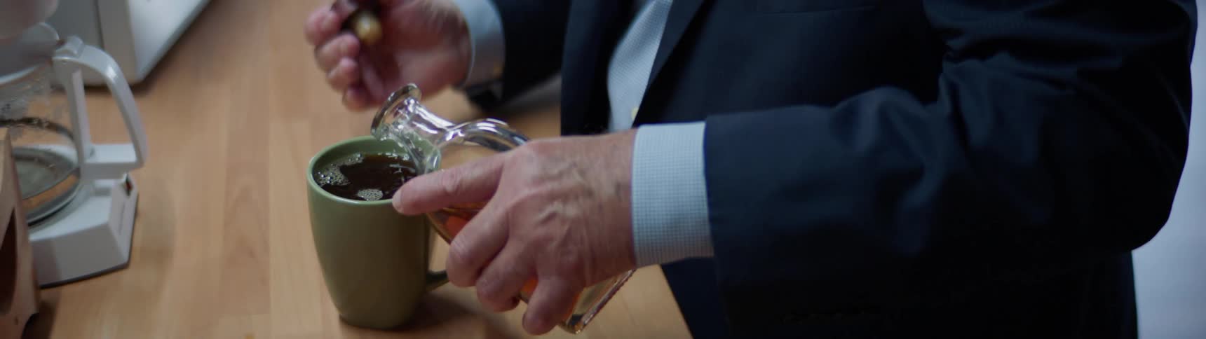 Alcoholic pouring alcohol into his coffee at the office in the morning