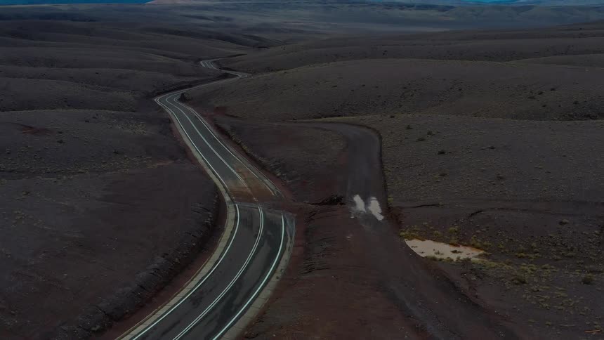 Aerial of curvy road in desert revealing storm clouds ahead