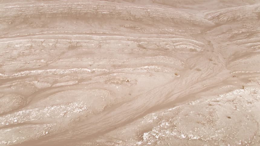A desert terrain with sand rocks and hills