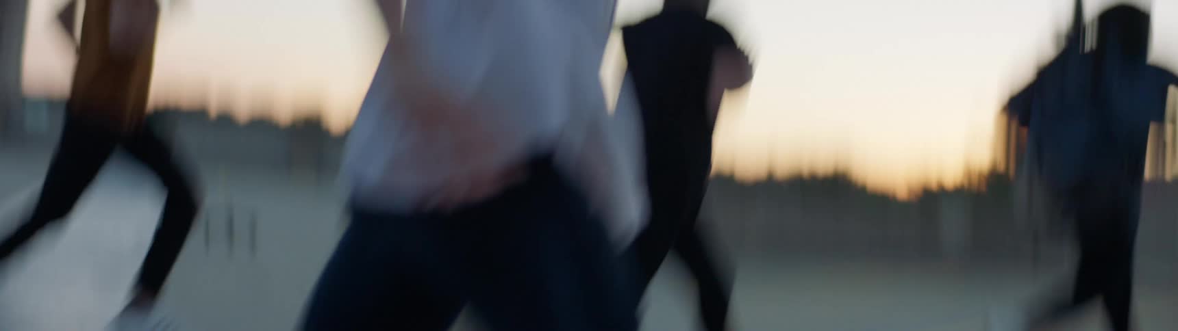 Group of friends running on the roof of a parking garage at sunset