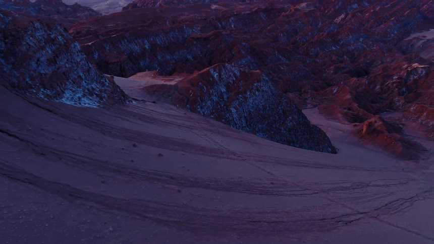 Red stoned outcroppings and mountains stretch between sandy desert and foggy horizon