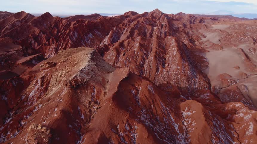 A mountain range in the badlands gives way to a deep and dark canyon