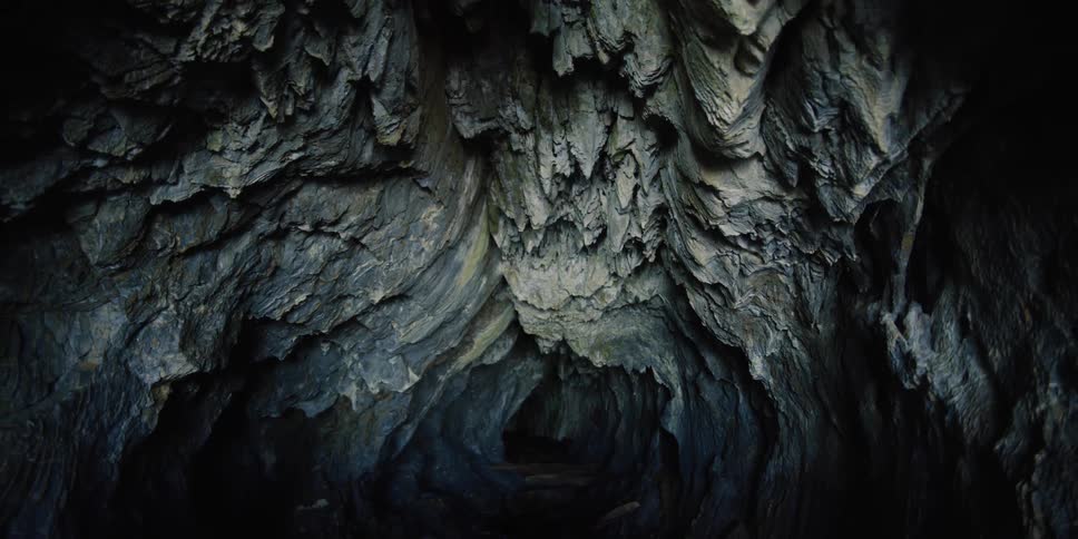 Inside view of dark cave leading to a tunnel in the distance
