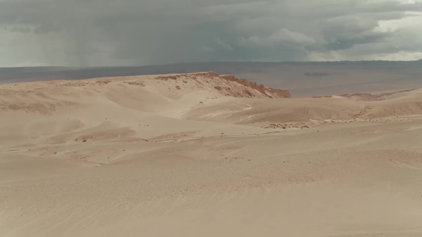 A rain storm sits on the horizon in a desert region