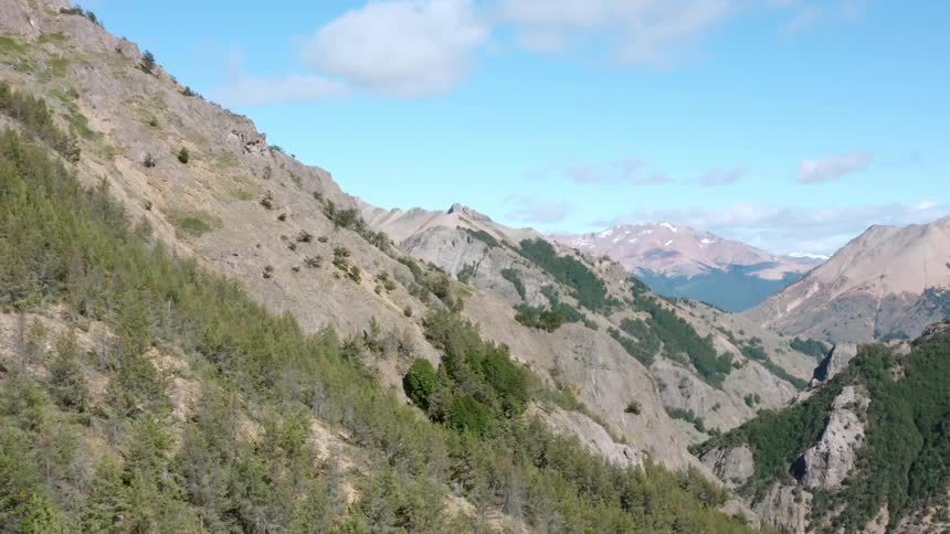 The brown and green slopes of a mountain range under a blue sky