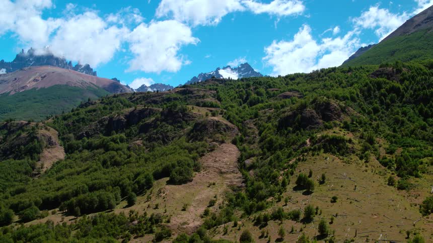 The green mountains lead to snow covered ones in the distance