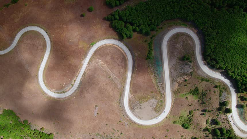 An aerial view of cars driving on a road is displayed