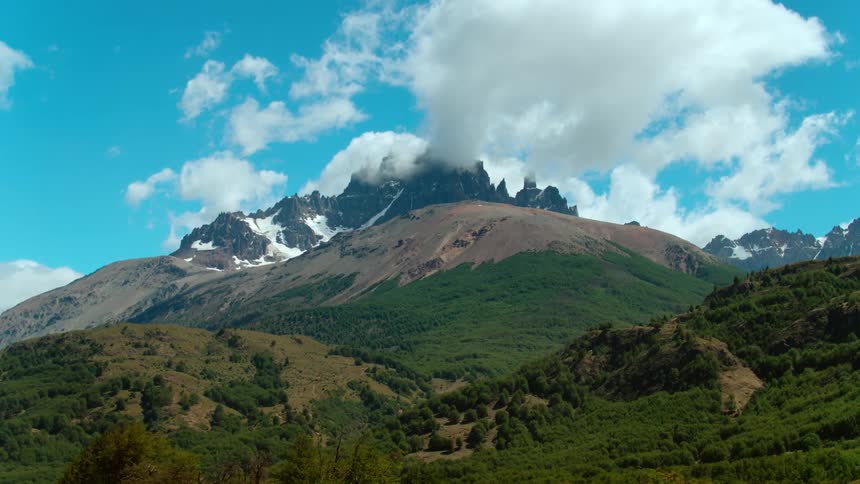 Snow covered mountain peak under the clouds at day