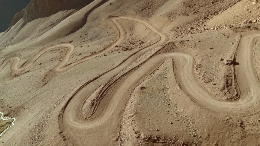 Aerial view of winding dirt road on the slopes of a deserted mountain