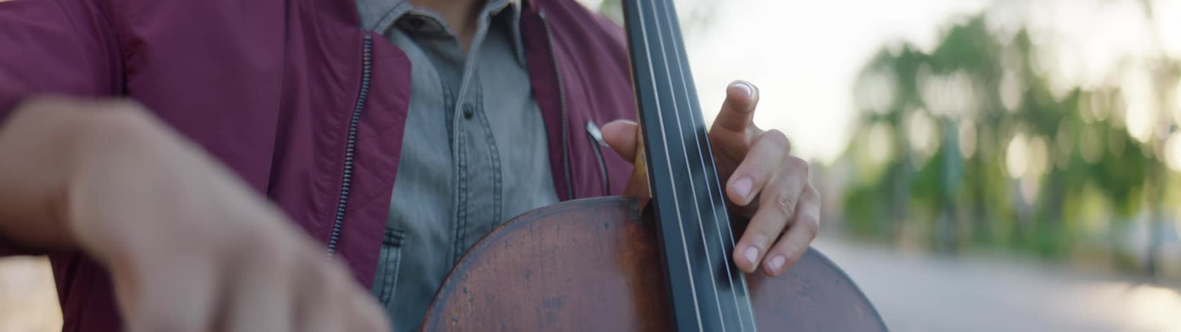 A man plays a cello on a city street