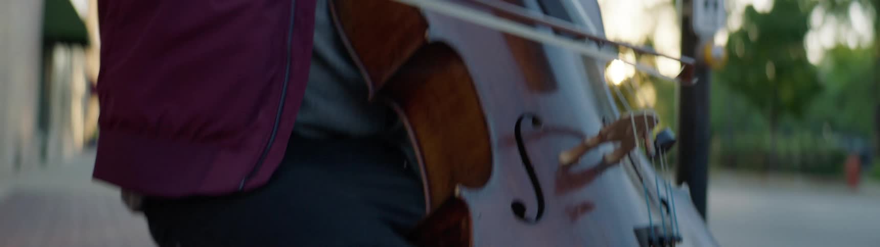 A white person busks for money with a stringed instrument
