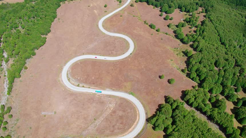 A bus and several cars navigate a road with many twists and turns
