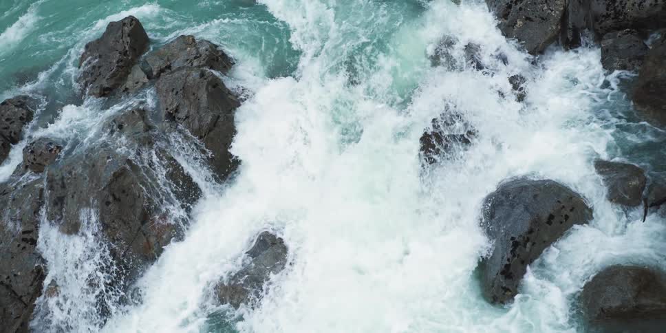 A waterfall rushes over large rocks