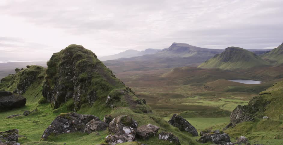 Rocky hills and the verdant valley below them under a cloudy sky