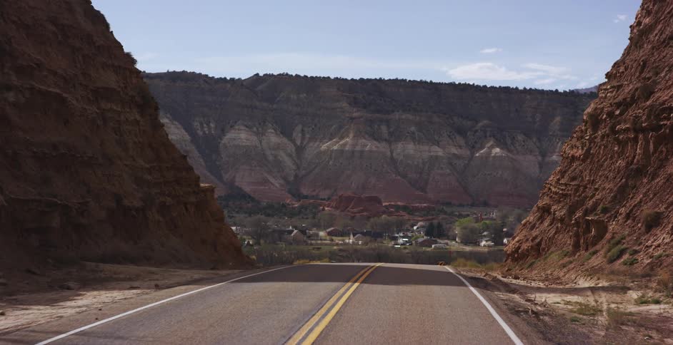 A mountain road between steep slopes leads to homes at the base of a ridge