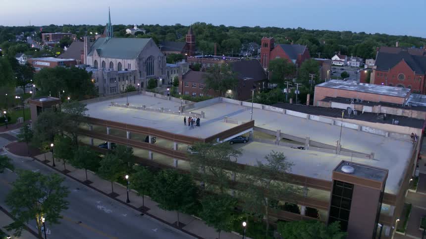 People standing on top of a parking lot with buildings and trees in the background