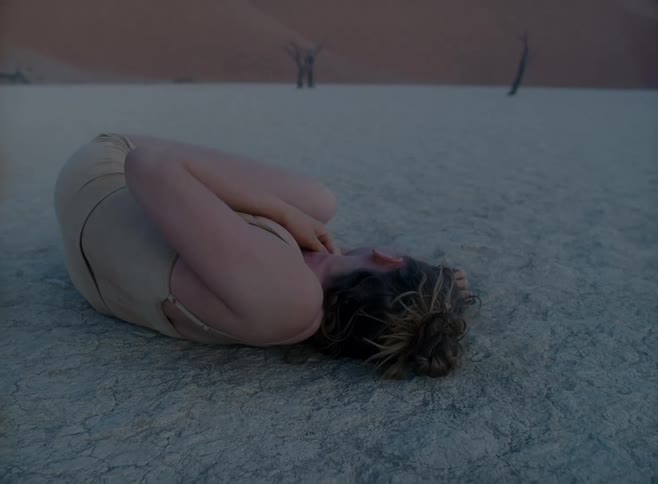 A teenager rolls around and dances in the desert
