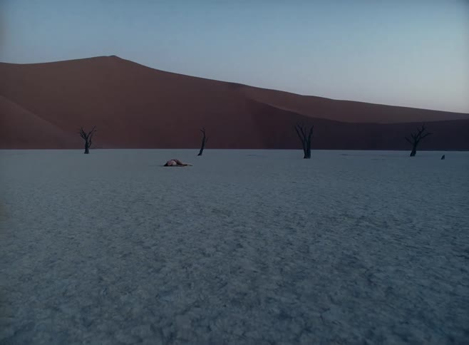 Woman laying on the floor in a desert at sunset