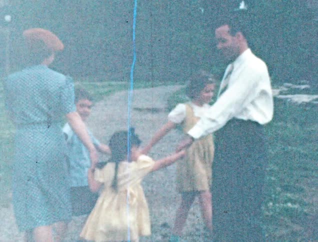 A father and mother play ring around the rosie with their three kids