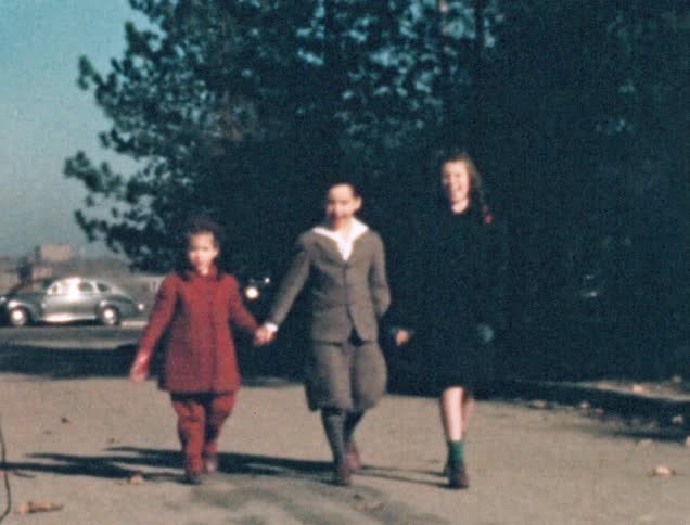 Three siblings walk along holding hands