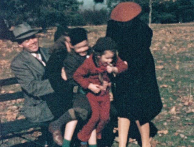 A white family goofs off in a park and tumbles off a park bench amidst laughter