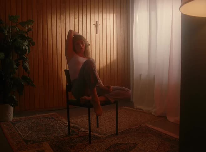 A young woman sits inside her house and smokes