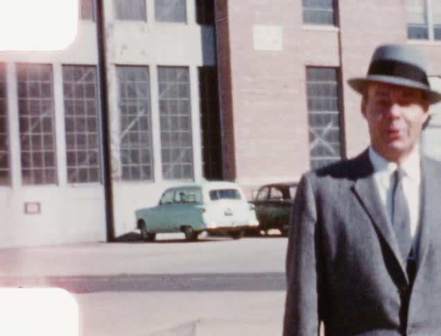 A man in a suit walks across a parking lot