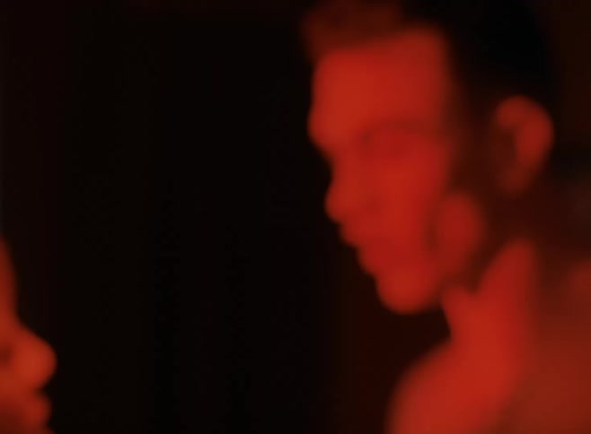 A man and woman verbally and physically fight in a room at night