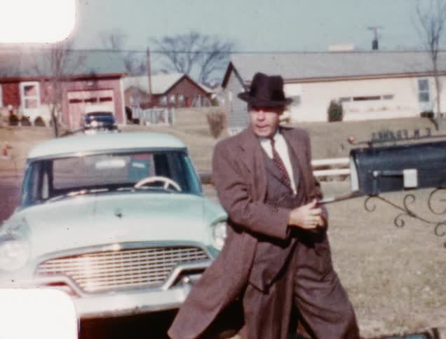 A man checks his mailbox and then walks towards his house