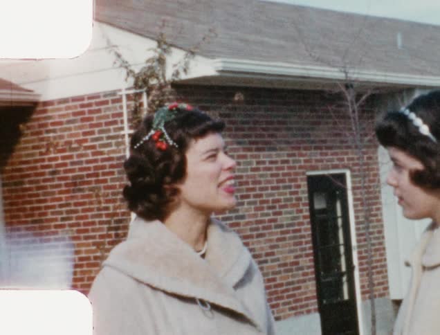 Two women stand outside talking and smiling and turning to look at the camera