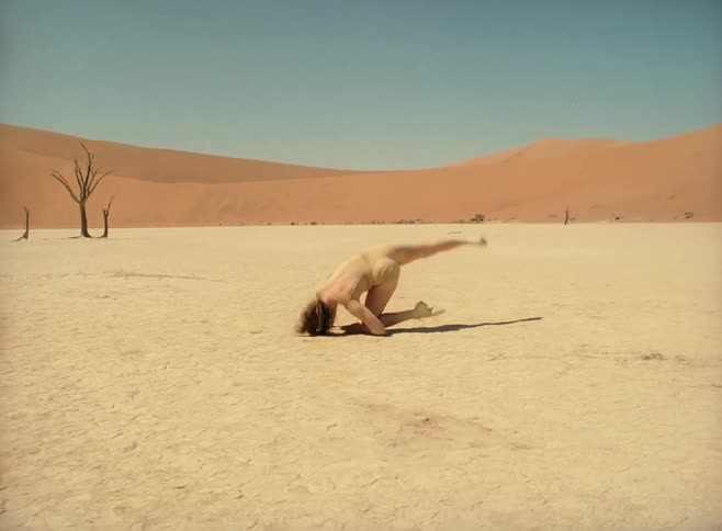 Dancer dancing in the desert with sand dunes in the background