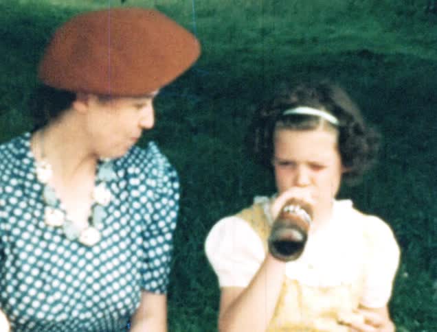 A mother and daughter eat and drink at a picnic