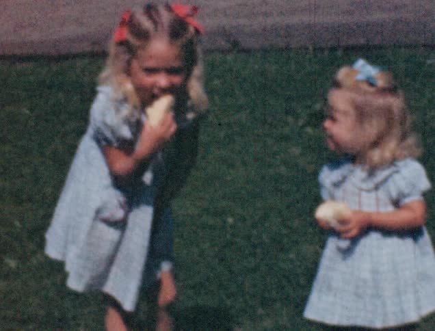 Girls wearing dress play with each other while eating cake in the lawn
